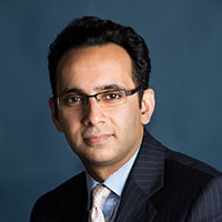 Portrait of a man in a suit and glasses against a blue background