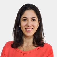 Smiling woman with shoulder-length dark hair wearing a red top against a white background